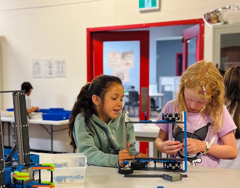 Two students assembling a VEX IQ robot together in class